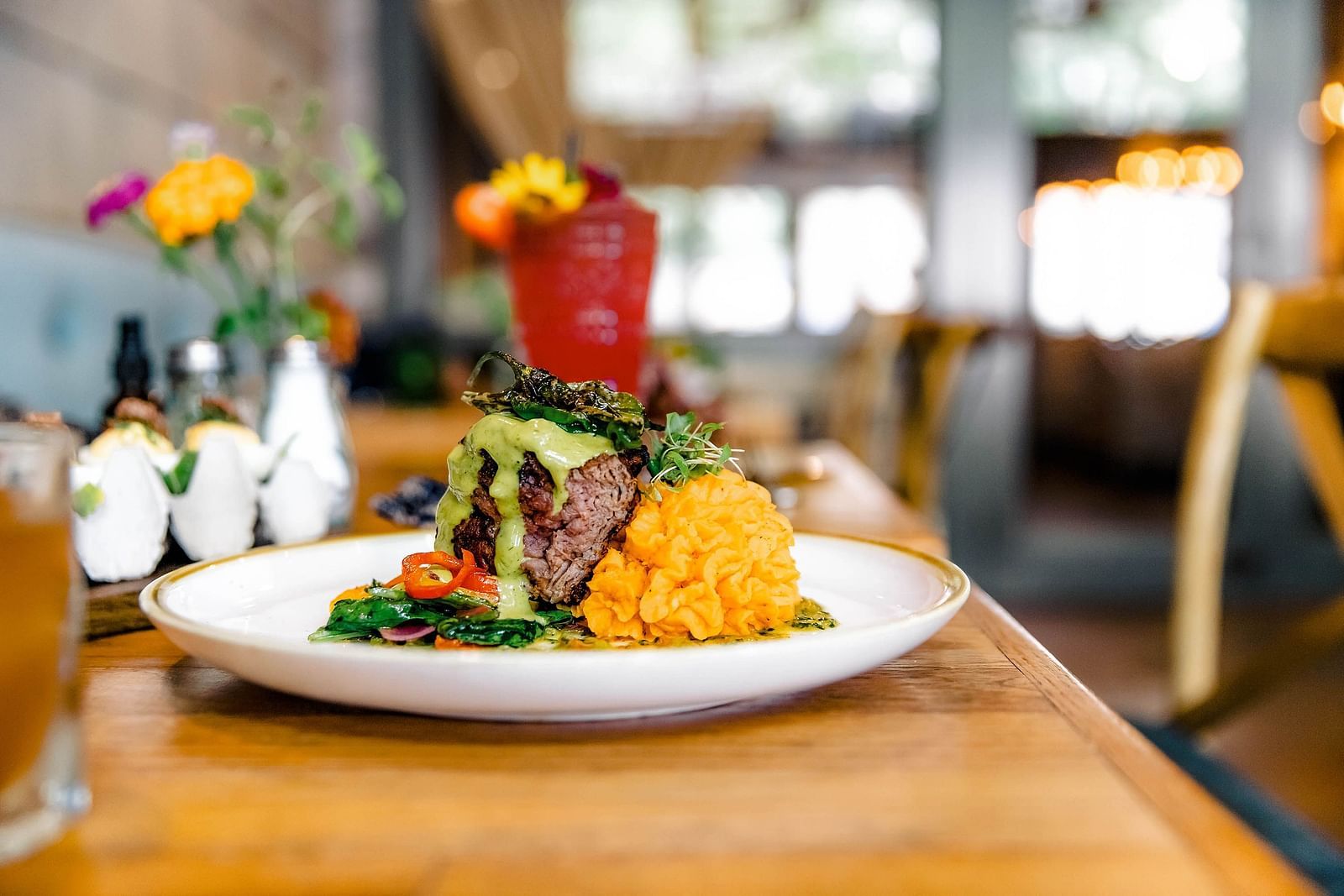 A plated meal and a drink in a modern restaurant setting.- The Grand Hotel & Ballroom, McKinney