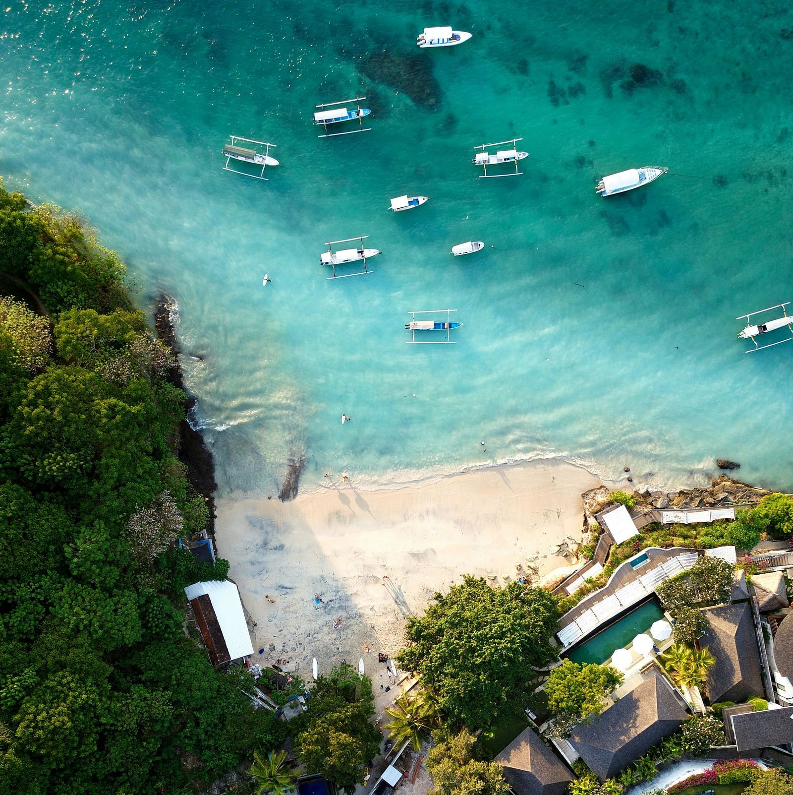 Aerial view of boats anchored near the shore and buildings along the coastline