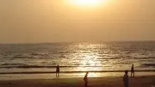 Sunset during the evening at a beach with a silhouettes of a few people.