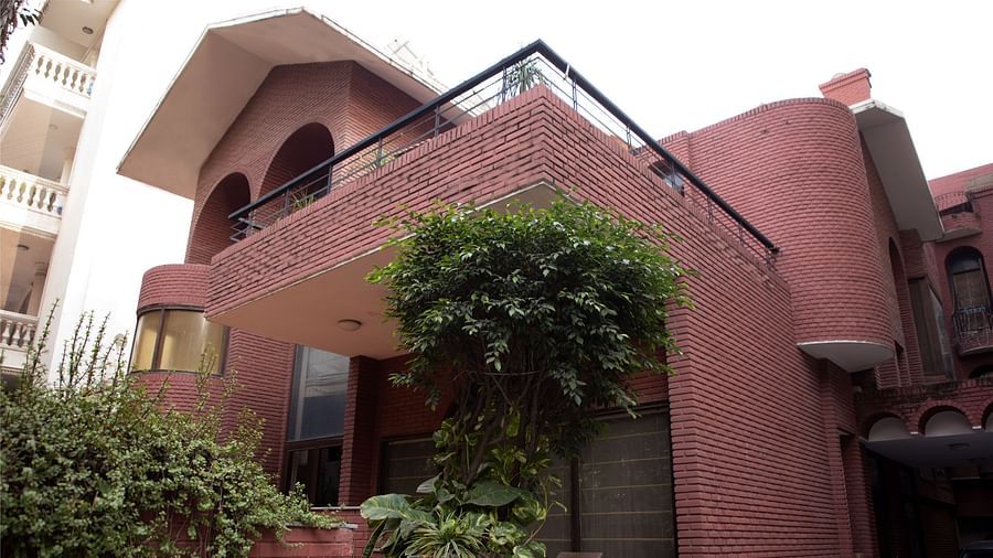 Redbrick Home - image of the facade featuring walls made from red bricks and plants growing in the premises