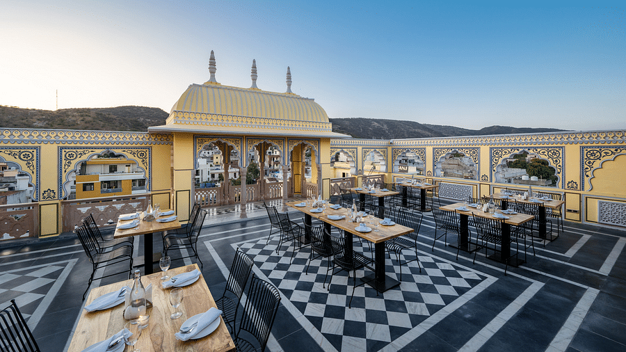 a roof top dining setup with beautiful views of the surrounding mountains and the early sunset - Brij Castle, Jaipur