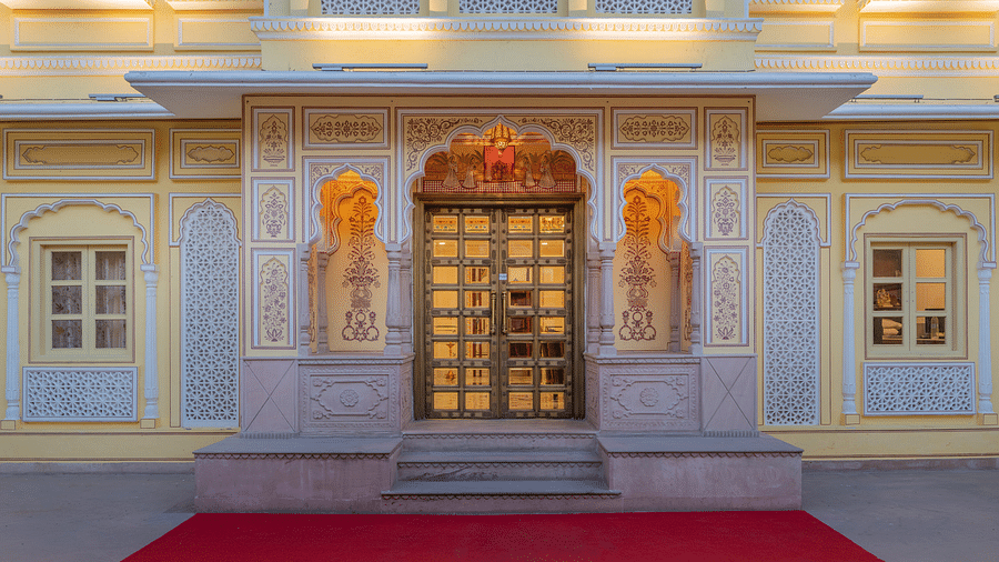 a close up stop of the entrance door with beautiful floral patterns painted on the wall - Brij Castle, Jaipur