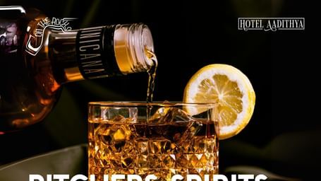 Promotional creative featuring liquor being poured in a whisky glass which has a lime stuck. On The Rocks bar is offering pitchers, spirits, veg and non-veg snacks at Hotel Aadithya.
