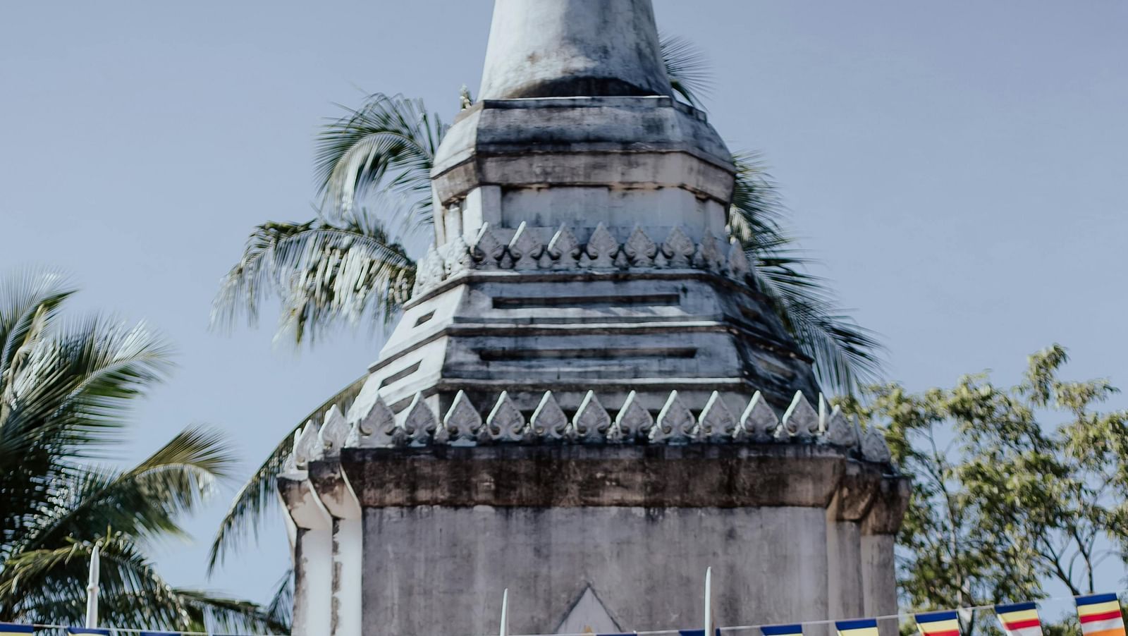 a woman standing on the steps in front of a temple with coconut trees in the background