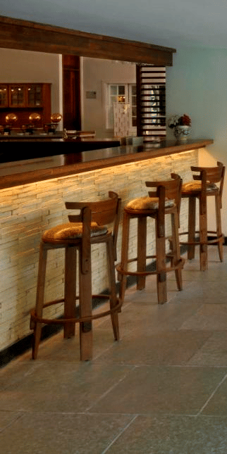 Modern covered patio with bar and white tables and chairs at Amanvana Spa Resort Coorg overlooking lush green surroundings.