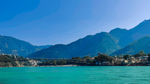 A serene turquoise lake surrounded by lush green mountains under a clear blue sky.