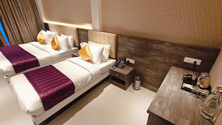 2 single beds with white linens and purple runners are positioned next to a wooden side table at Bliss Casa Mila By Bergamont Hotels, Kodaikanal.