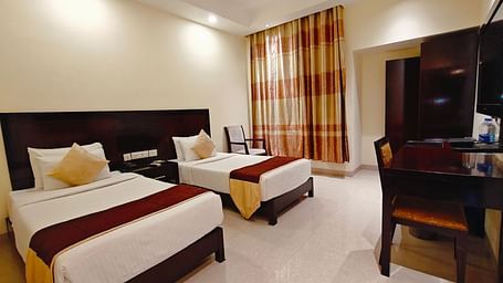 Well-lit twin-sharing guest room at Hotel Alps Residency, Krishnagiri, with modern furnishings.