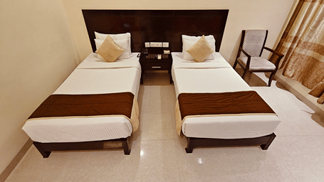 Clean and spacious twin-bed accommodation with warm lighting at Alps Residency, Krishnagiri.