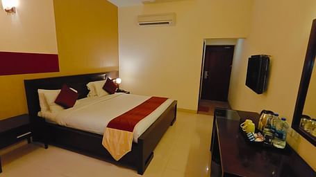 King bed room with warm lighting and functional furniture at Hotel Alps Residency, Krishnagiri.