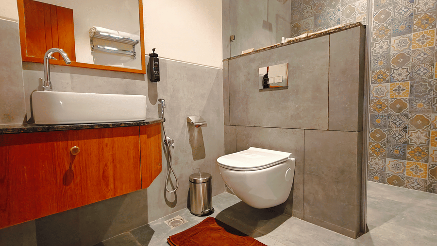 A modern bathroom at Bliss Giriya By Bergamont Tiruvannamalai with a wash basin, wall-mounted toilet, and stone-clad wall.