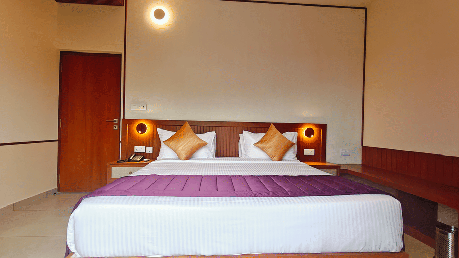 A neatly arranged room at Bliss Giriya By Bergamont Tiruvannamalai with a double bed and wooden wardrobe unit.
