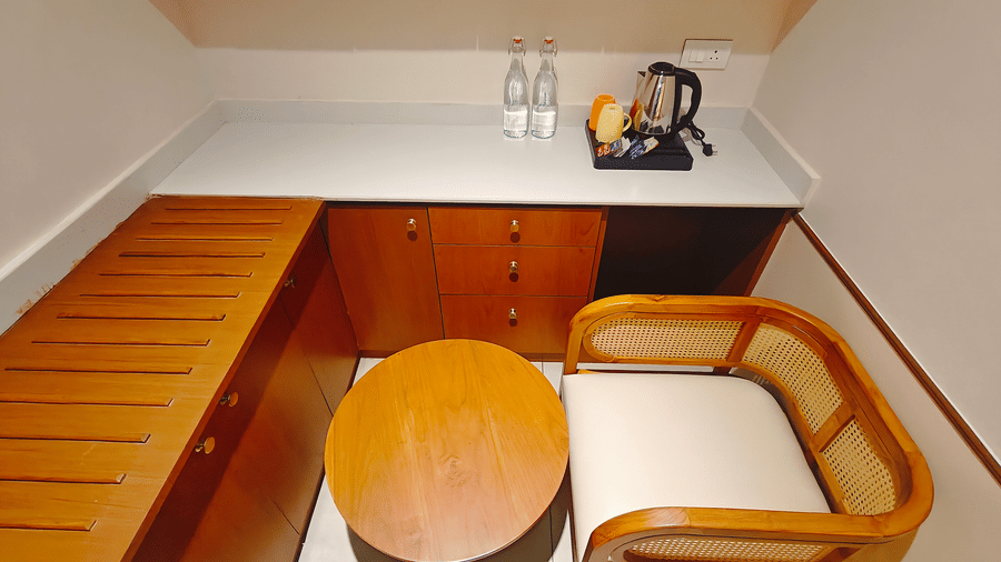 A room pantry area at Bliss Giriya By Bergamont Tiruvannamalai with a countertop, kettle, water bottles, and a compact sofa seating arrangement.
