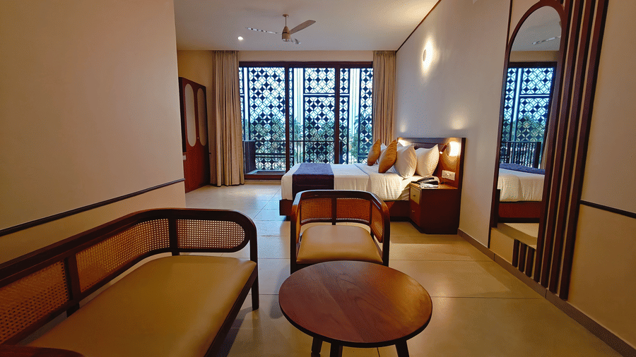 A hotel room at Bliss Giriya By Bergamont Tiruvannamalai with a sitting area, table, chairs, and a balcony door.