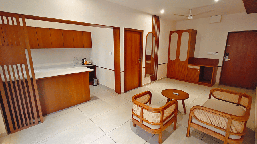 A suite interior at Bliss Giriya By Bergamont Tiruvannamalai with wooden cabinetry, a kitchenette counter, and a seating arrangement.