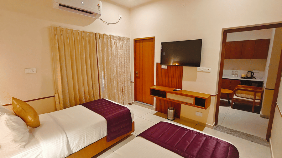A hotel room at Bliss Giriya By Bergamont Tiruvannamalai with a double bed, wall-mounted television, and wooden storage unit.