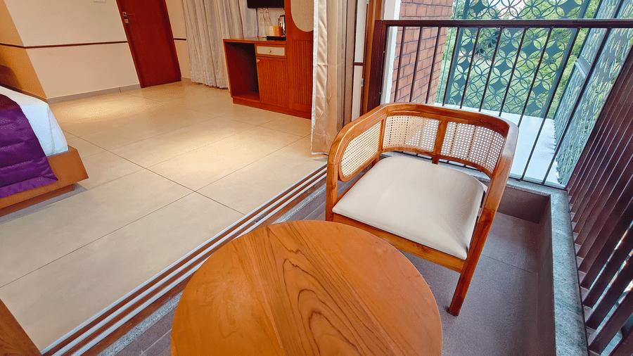 A twin-bedded room at Bliss Giriya By Bergamont Tiruvannamalai with wooden flooring and large windows overlooking greenery.