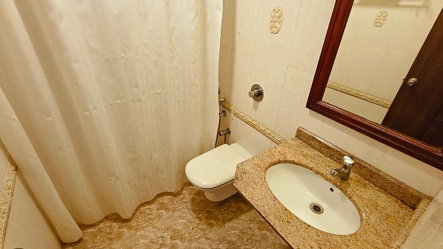 Compact bathroom with shower curtain, sink, and toilet at Hotel Alps Residency, Krishnagiri