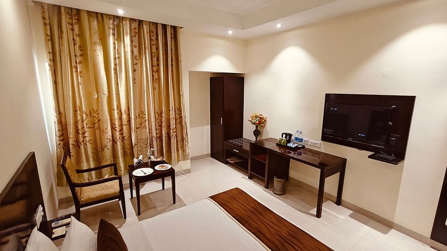Spacious guest room with double bed, seating area, and TV at Hotel Alps Residency, Krishnagiri.