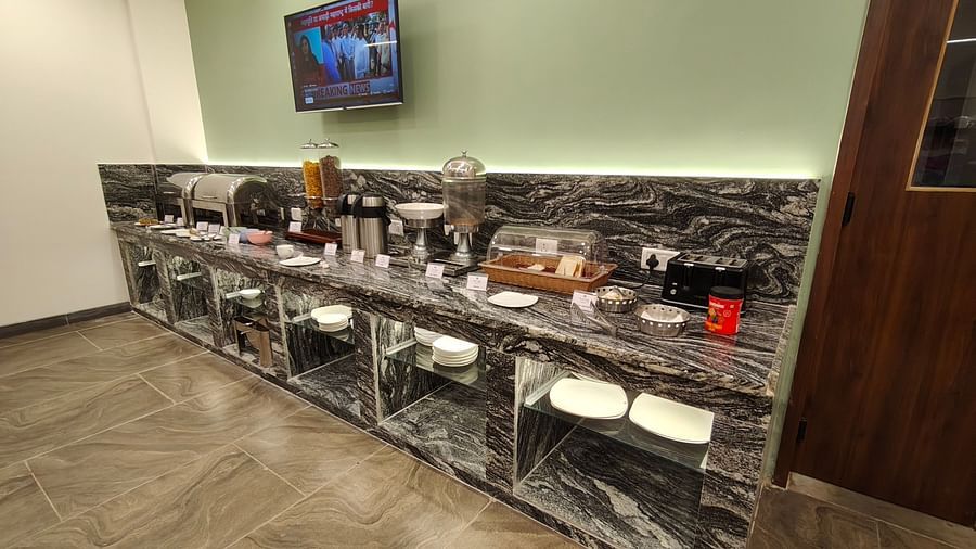 Buffet counter setup with various serving dishes and a mounted TV