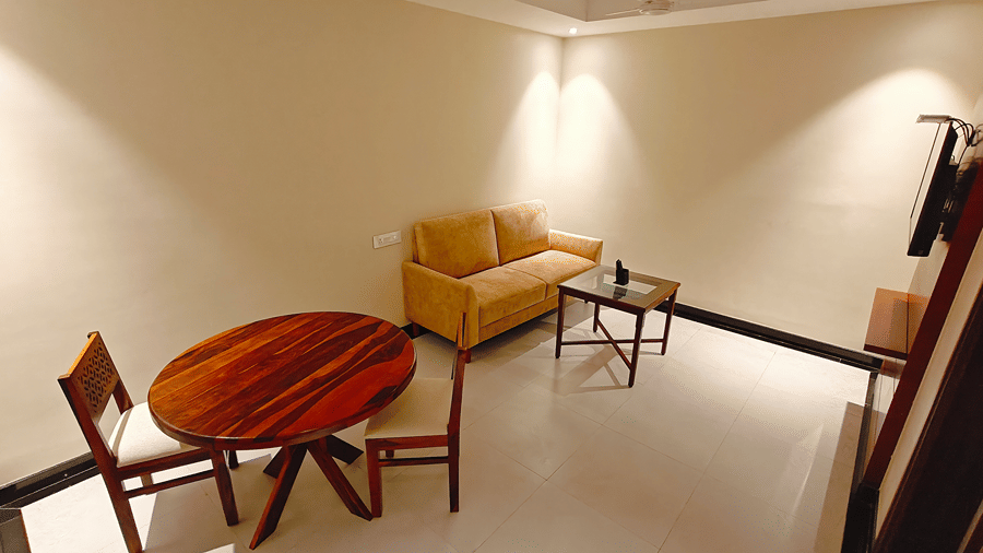 A seating area with a sofa, a table, chairs, a bulb, and a mirror. | MM Legacy, Kanchipuram
