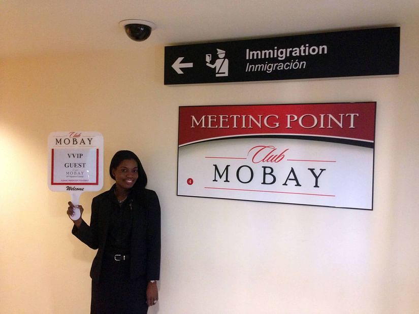 An image of a women standing with a signboard in her hand near the Club Mobay arrival