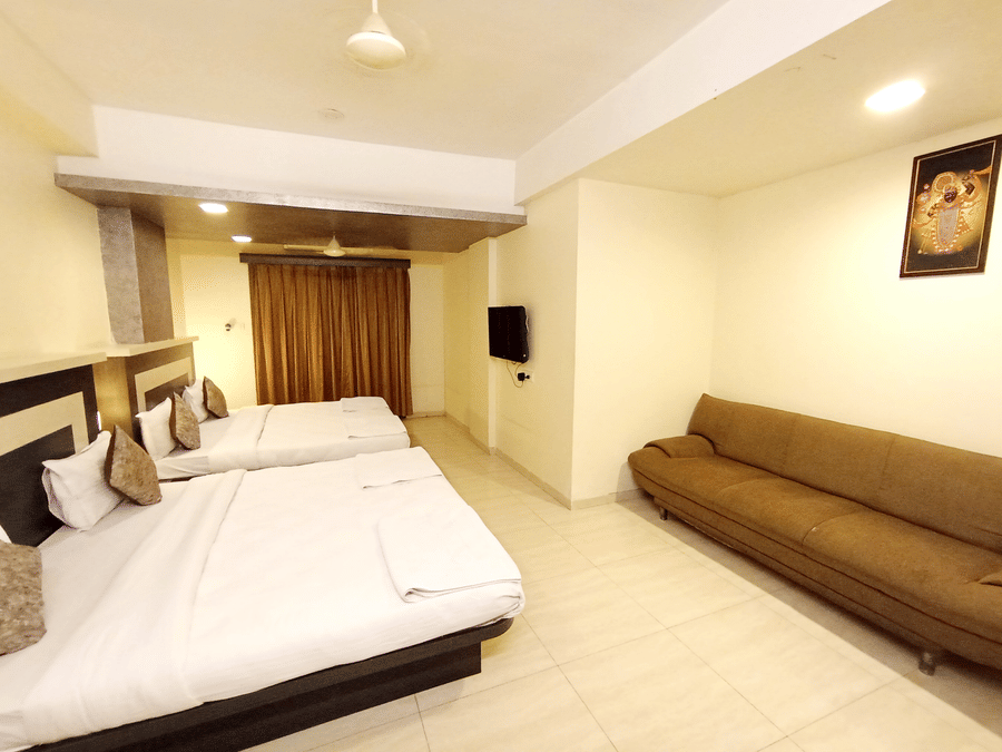 Well-lit family room showcasing a sitting area with a brown sofa couch next to multiple large beds.