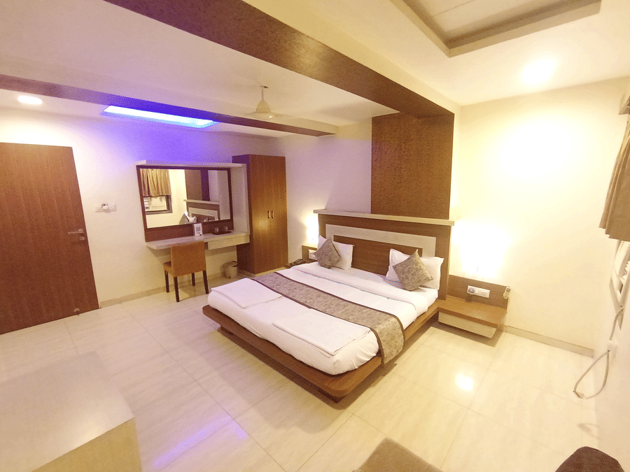 Wide view of the suite room with a double bed, dressing mirror desk, and accent strip lighting on the ceiling.