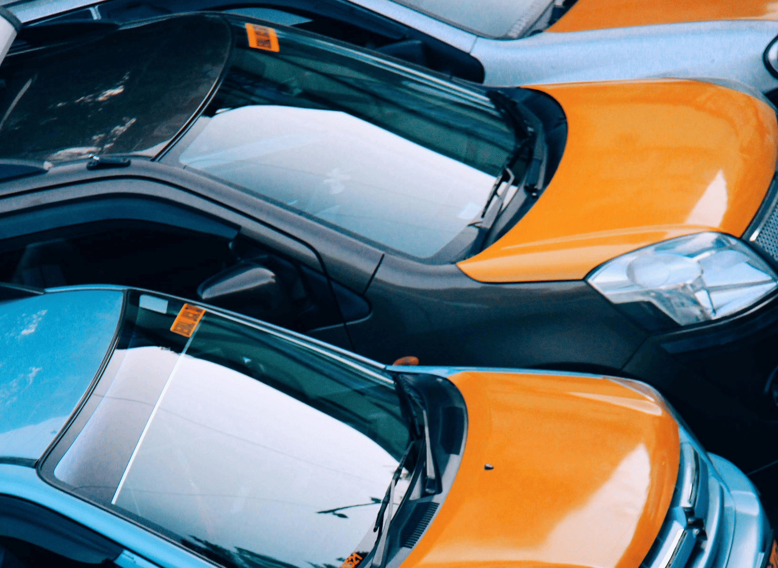 A row of car parked side-by-side in a lot.