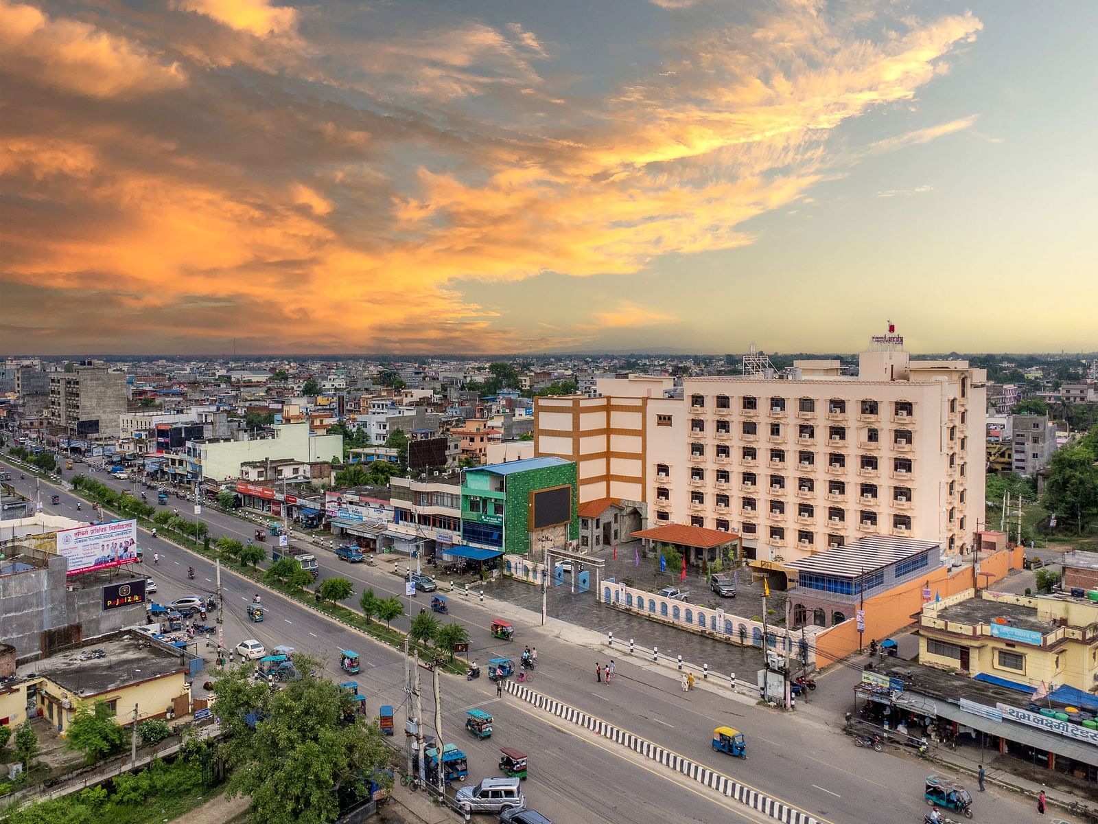 Aerial view of Diamond Palace Lords Plaza in Nepalgunj amidst a cityscape under a dramatic, colorful sky.
