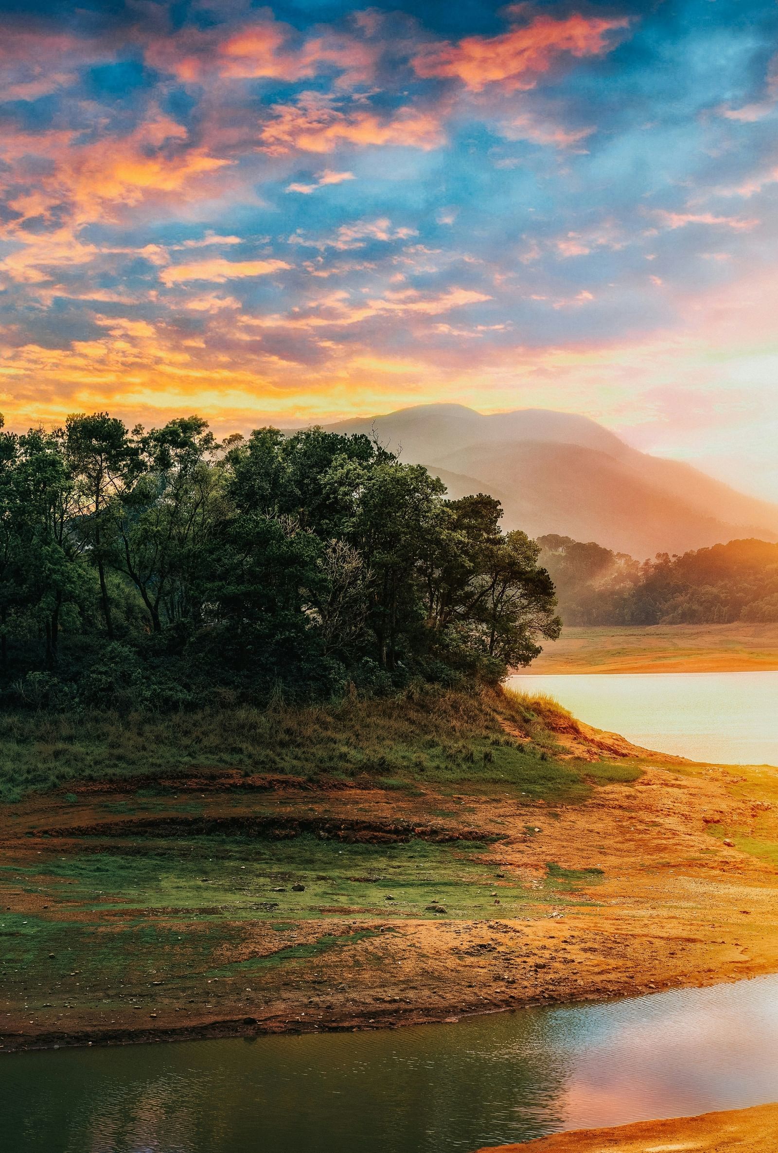 A scenic lake at sunrise with orange-pink sky reflecting on water.