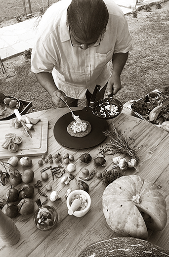 A person preparing food at an outdoor setup with vegetables and plates at Karma Chalets.