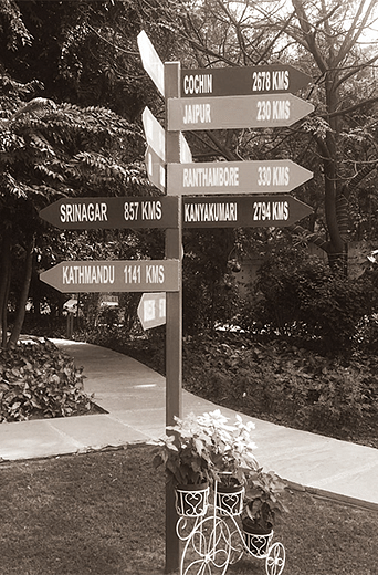 Directional signpost in a garden area showing various locations within Karma Chalets.