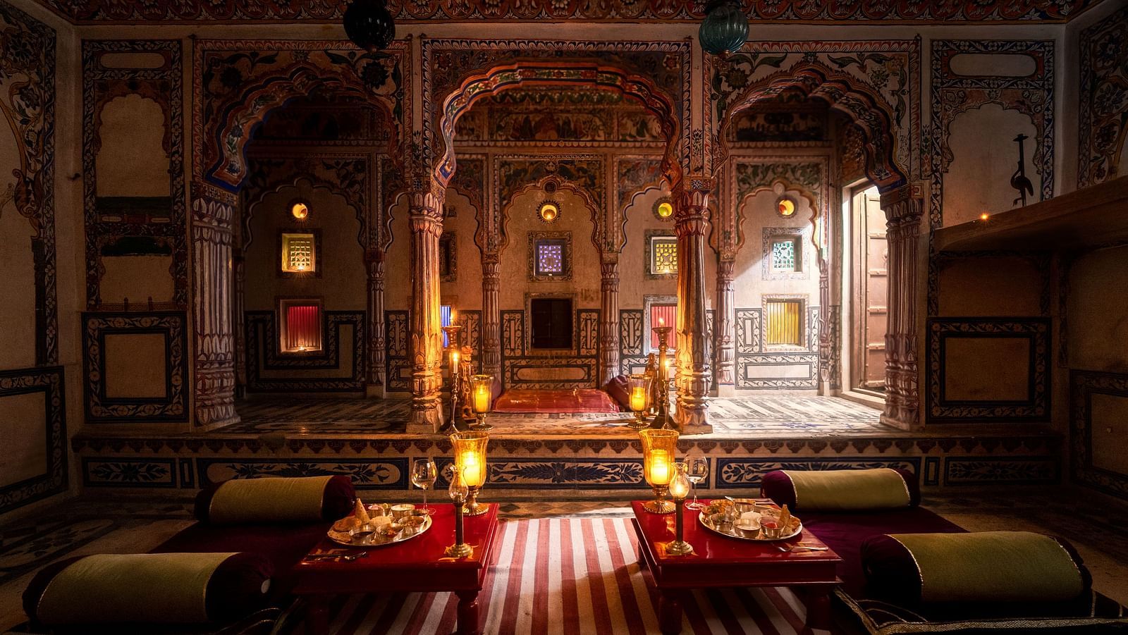 A wide view of the interiors of a room with palatial architecture and dining arrangement