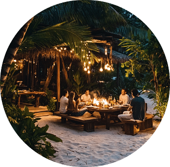 People dining in an outdoor setting on the beach surrounded by lush greenery