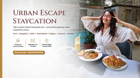 A woman in a robe stretches with a relaxed smile, enjoying a delicious breakfast spread on a table in front of her.