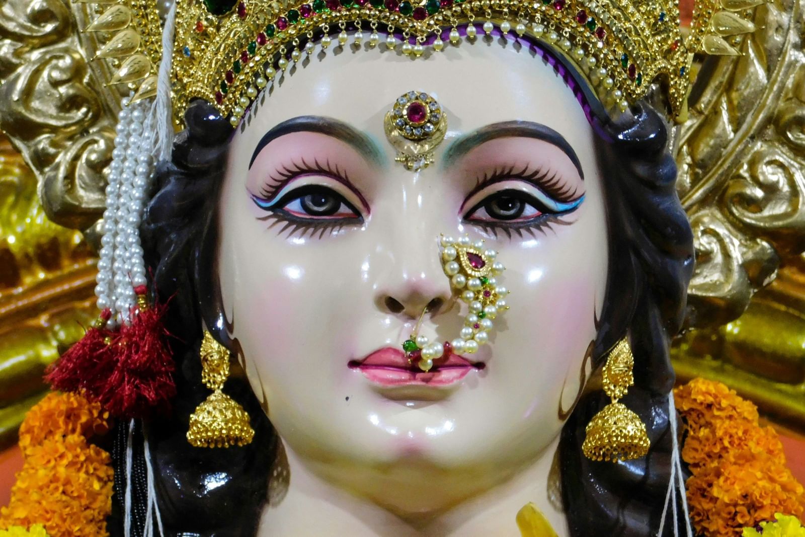 A close-up of a beautifully adorned idol of a Hindu goddess, with elaborate jewelry and makeup.