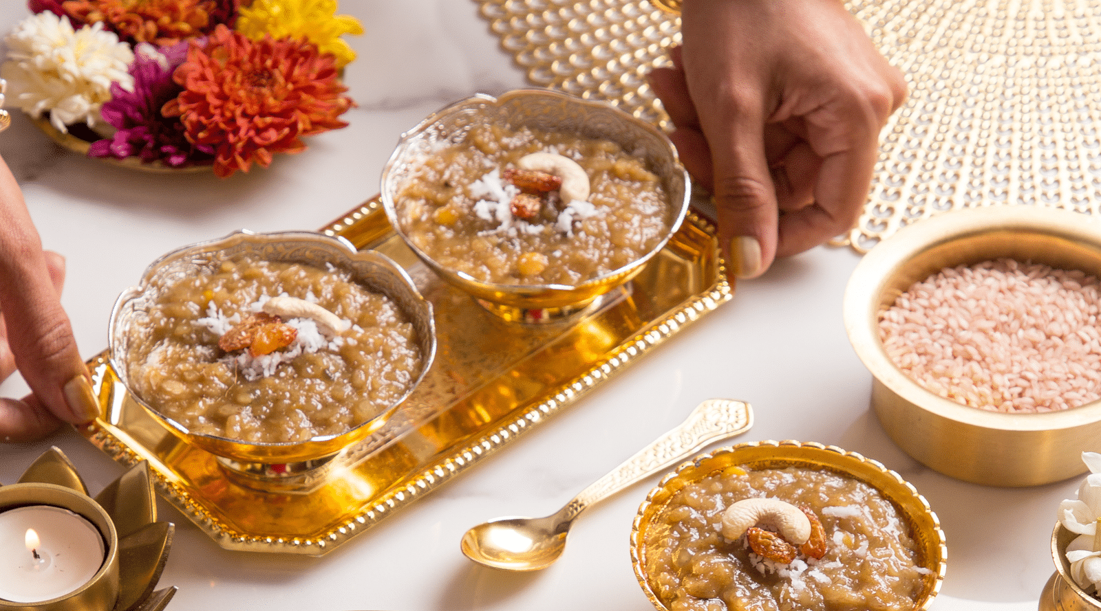 An image of a bowls with varieties of desserts garnished with dry fruits and placed on a table next to scented candles - Kamats India