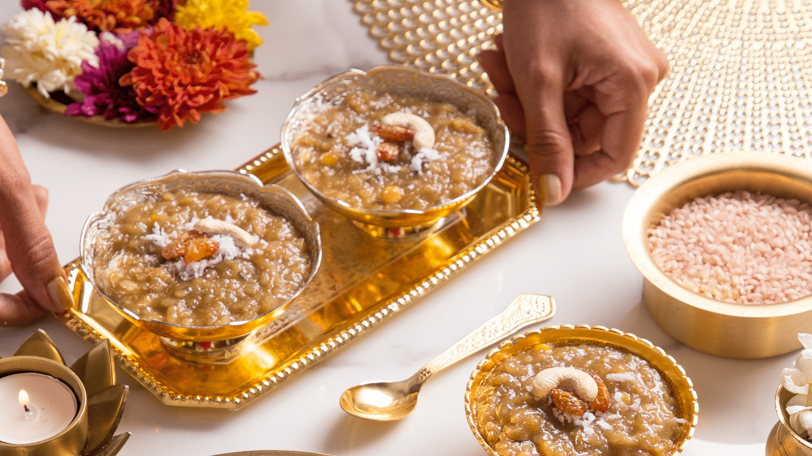 An image of a bowls with varieties of desserts garnished with dry fruits and placed on a table next to scented candles - Kamats India