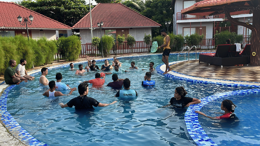 Guests participating in a group water activity or pool game in the large outdoor swimming pool - DAN Resorts & Weddings, Palghar