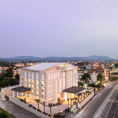 MJ Sarovar Portico hotel building alongside a bustling road, set against a scenic mountain view - MJ Sarovar Portico, Haridwar