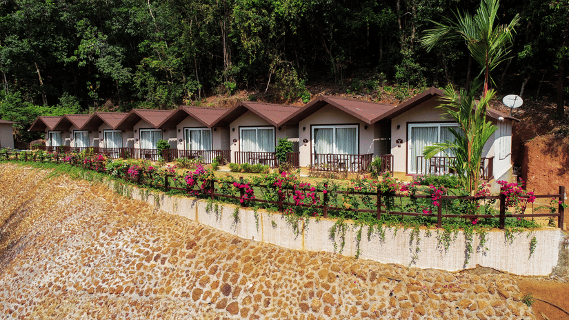 An aerial shot of the cottages surrounded by lush green trees and flowers seen on a sunny day - Stone Wood Nature Resort, Gokarna