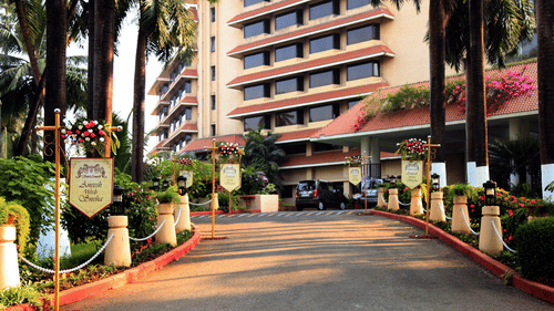 A driveway leading to The Retreat Hotel and Convention Centre, with trees and decorations framing the path and a building in the background.