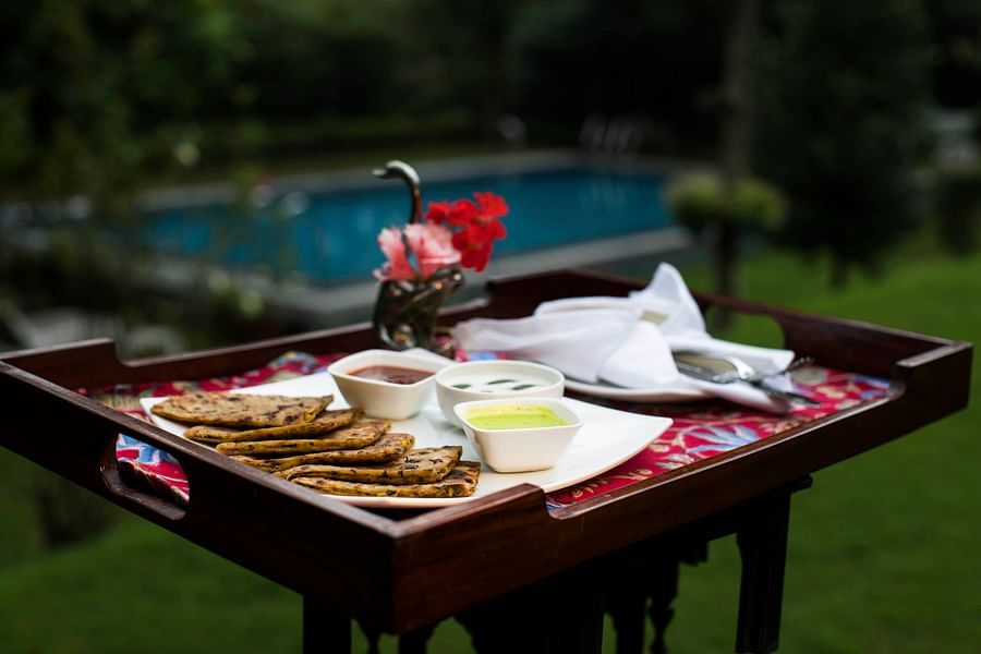 A breakfast tray with pancakes and dips, set up outdoors with a pool in the background.