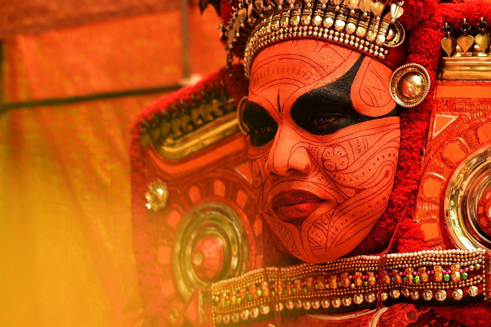 an image of a person painted his face to perform Theyyam an artform in Kerala - Kumarakom Tourism