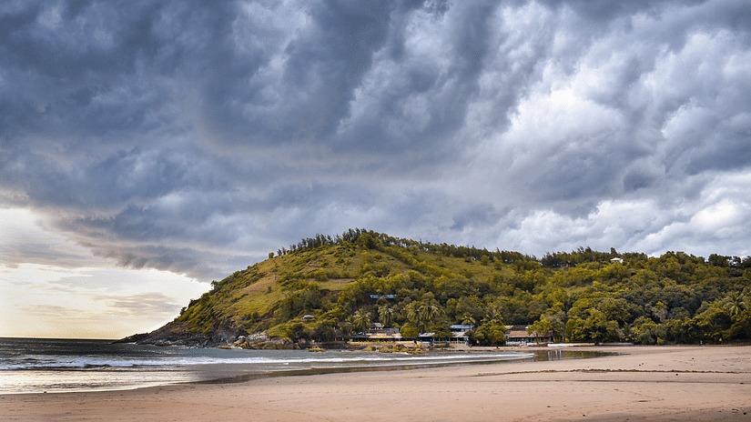 an image of a beach with powdery white sand a calm sea surrounded by a hill