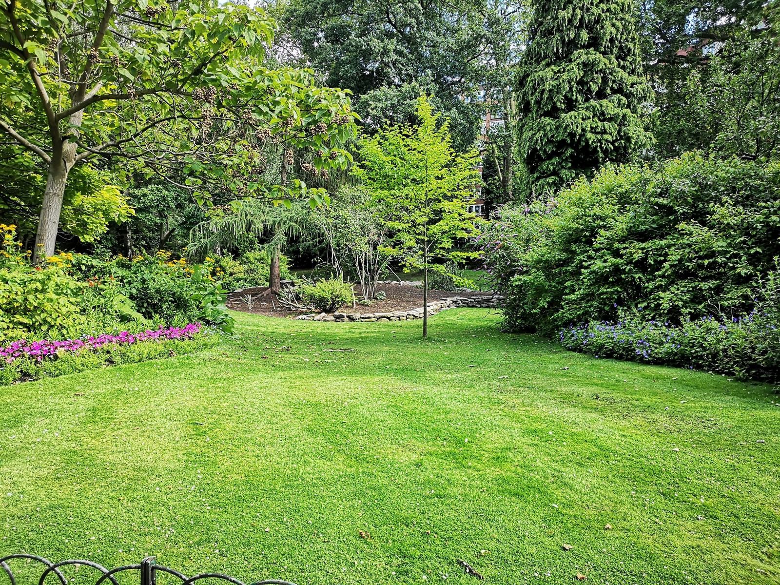 A lush green lawn surrounded by dense trees and flowering plants.