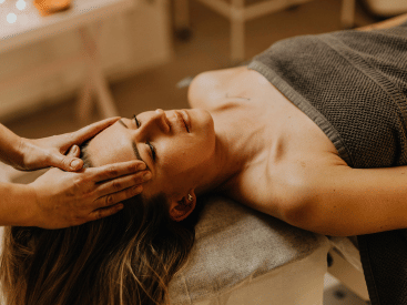 A woman in a head massage session, eyes closed, serene.