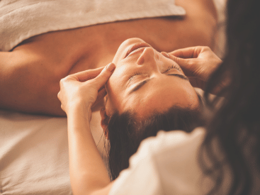A person receiving a soothing facial massage, hands gently on temples.