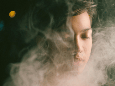 A serene face with eyes closed, surrounded by a cloud of mist or steam.
